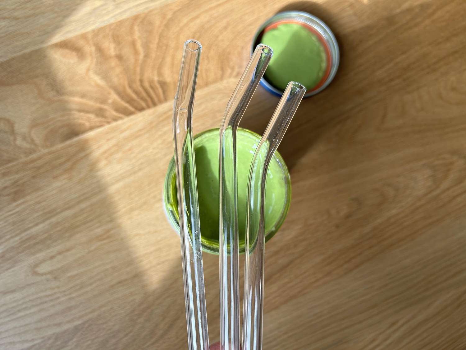 Three glass straws held over a smoothie