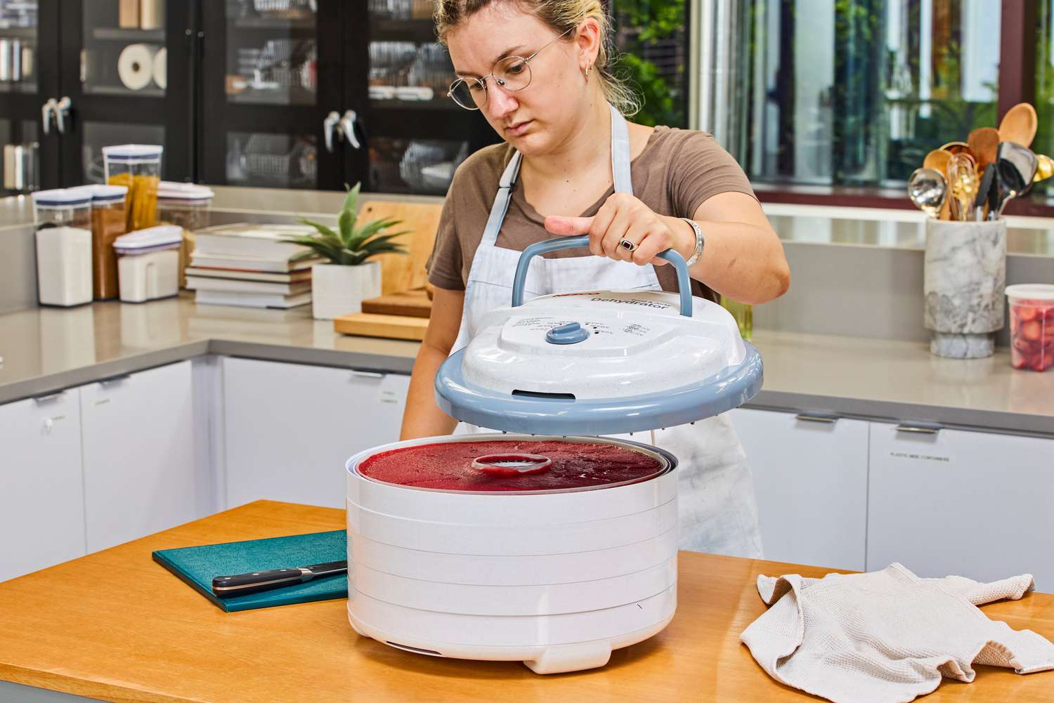 A person opening the lid of Nesco Snackmaster Pro Food Dehydrator