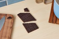 An unwrapped dark chocolate bar on a kitchen countertop.