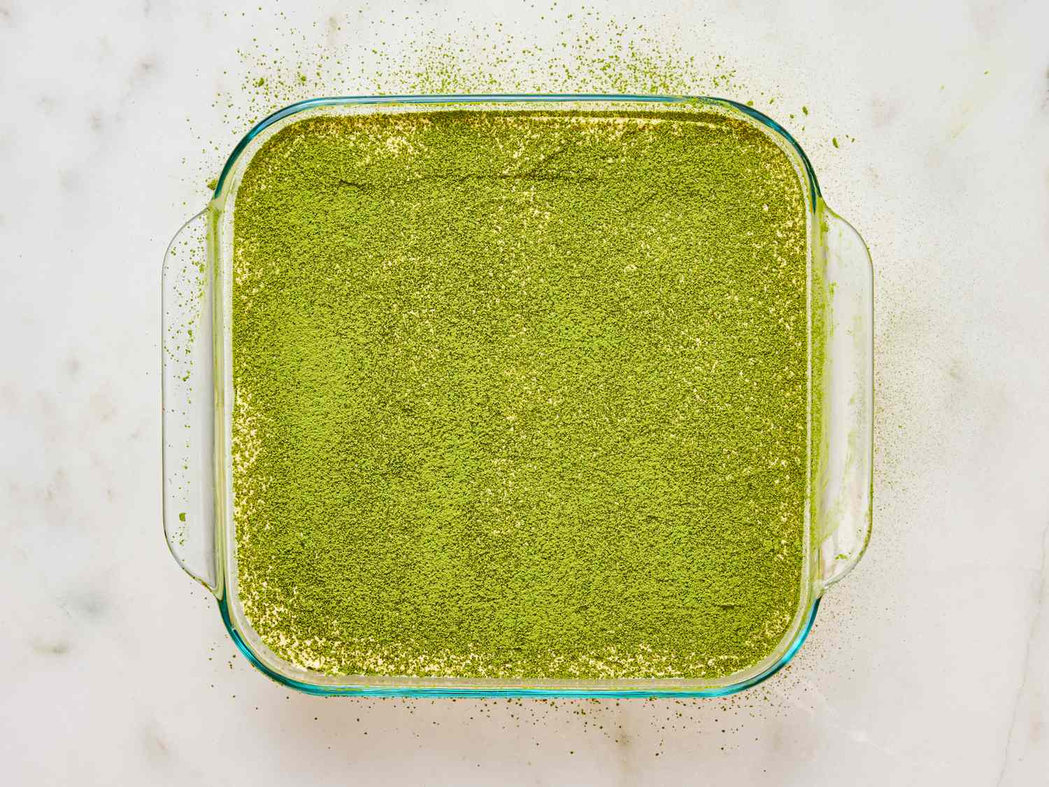 A dish of tiramisu with a layer of matcha powder on top