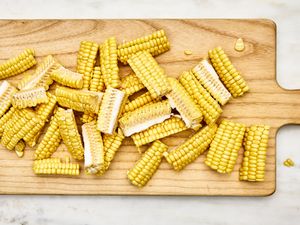 Corn cobs sliced into segments on a wooden cutting board