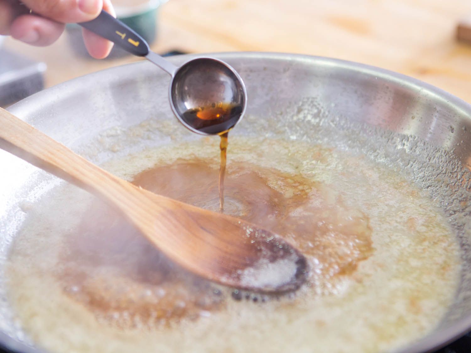Tablespoon of vinegar poured into a pan of simmering butter and sugar.
