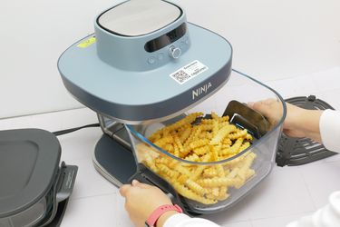 a person removing a basket of fries from the ninja crispi pro