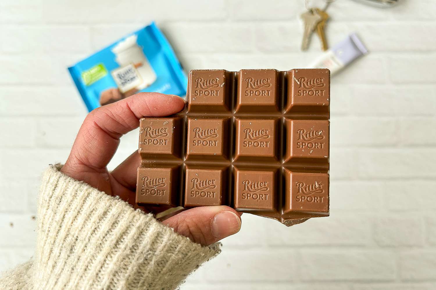 A person holding a bar of Ritter Sport Alpine Milk Chocolate