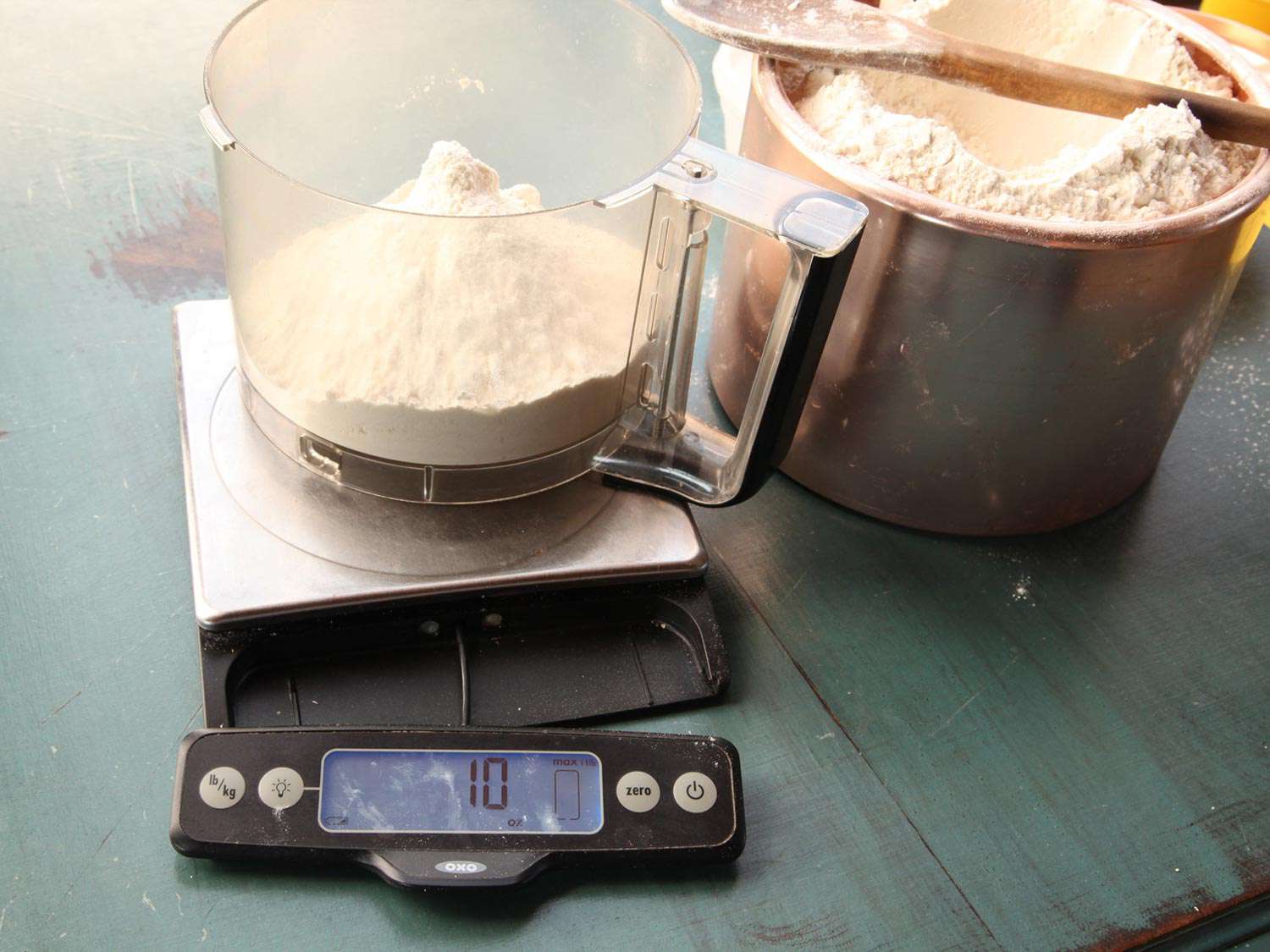 Flour is weighed in a food processor bowl that has been placed on a digital scale.