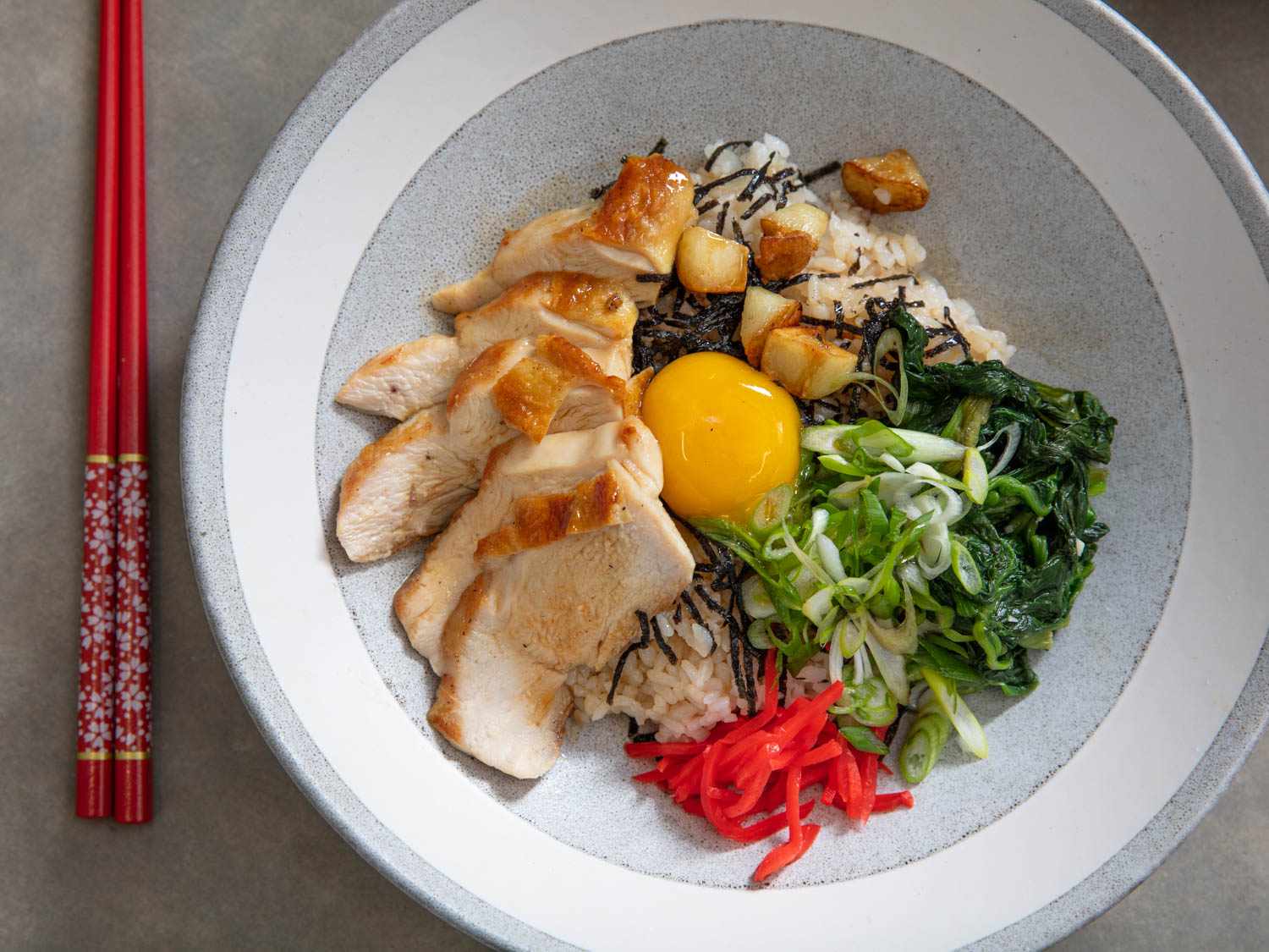 Overhead view of an assembled bowl of chicken donburi with the optional egg yolk garnish, ready to serve.