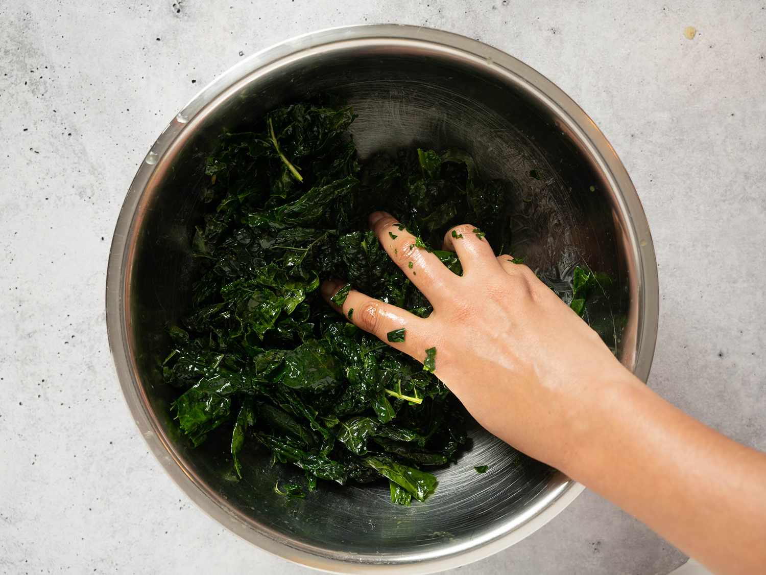 Massaging kale with olive oil in a large bowl for salad