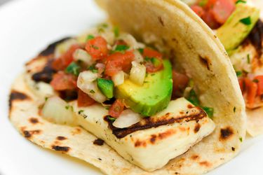 close-up of charred grilling cheese soft taco with avocado and pico de gallo