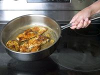 a person holding a pan with seared chicken inside