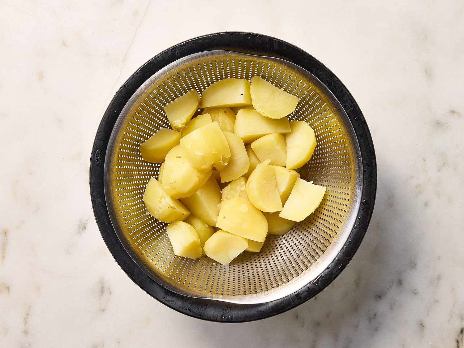 boiled diced potatoes in strainer 