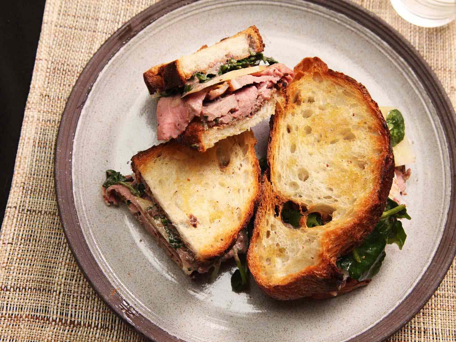 A plate of leftover lamb sandwiches with tapenade mayo, watercress, and caciocavallo cheese.