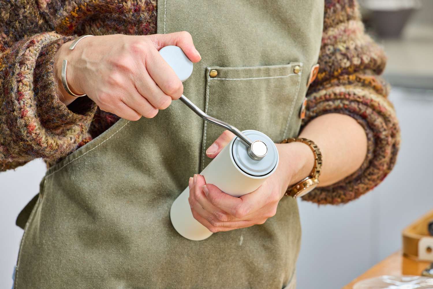 A person grinds the crank on the top of the Timemore C2 Max Manual Grinder