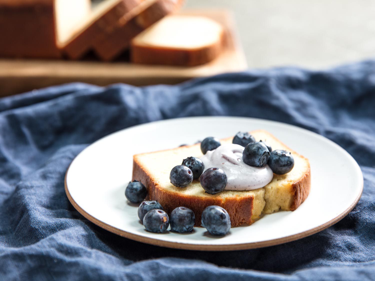 A slice of golden pound cake with whipped cream and blueberries. 