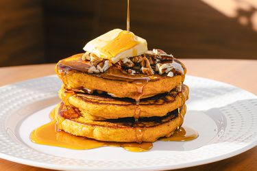 Stack of pancakes with pecans butter and syrup on top