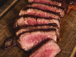 Slices of cooked steak arranged on a wooden surface