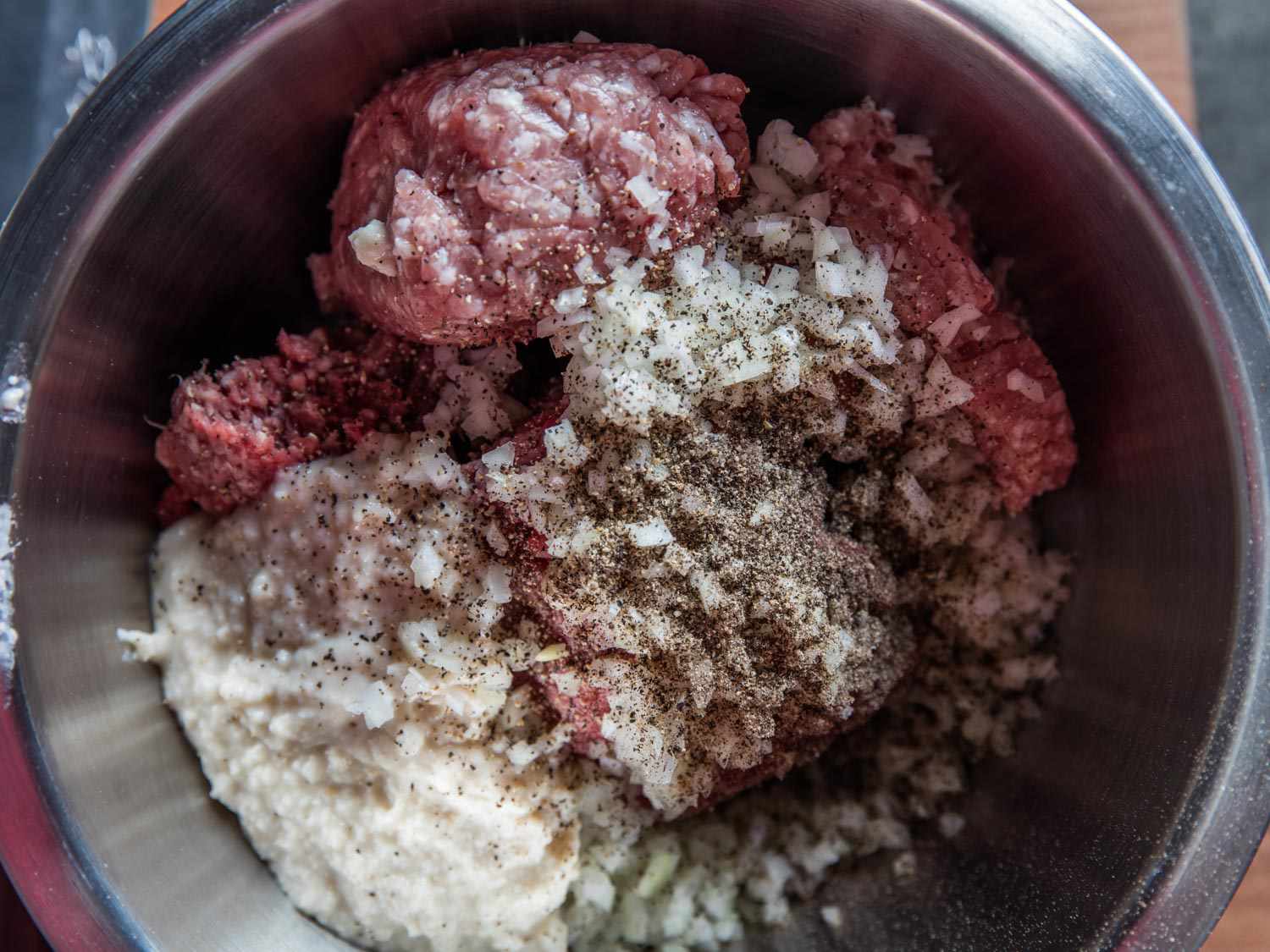 Overhead view of all of the ingredients for Salisbury steak patties in a mixing bowl, ready to be mixed.