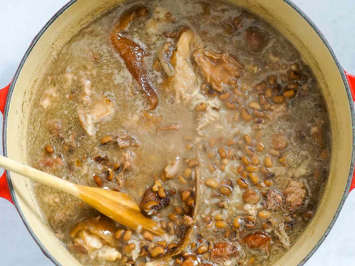 Seasoning stirred in with a wooden spoon into the ham hock mixture.