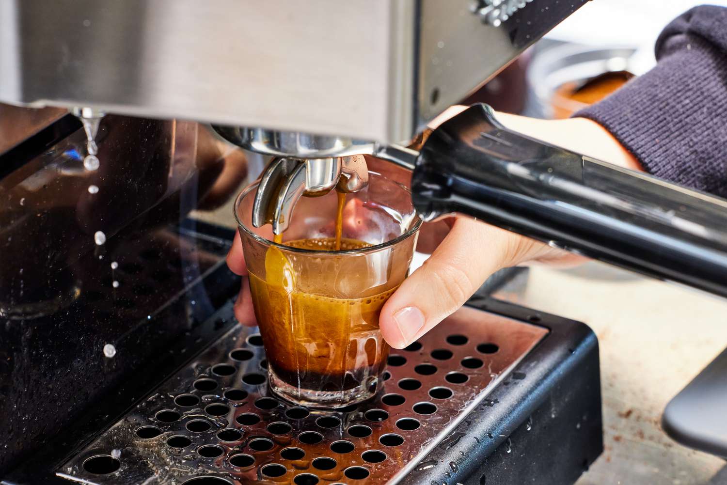 A hand holding a cup as an espresso brews from the Gaggia Classic Pro Espresso Machine