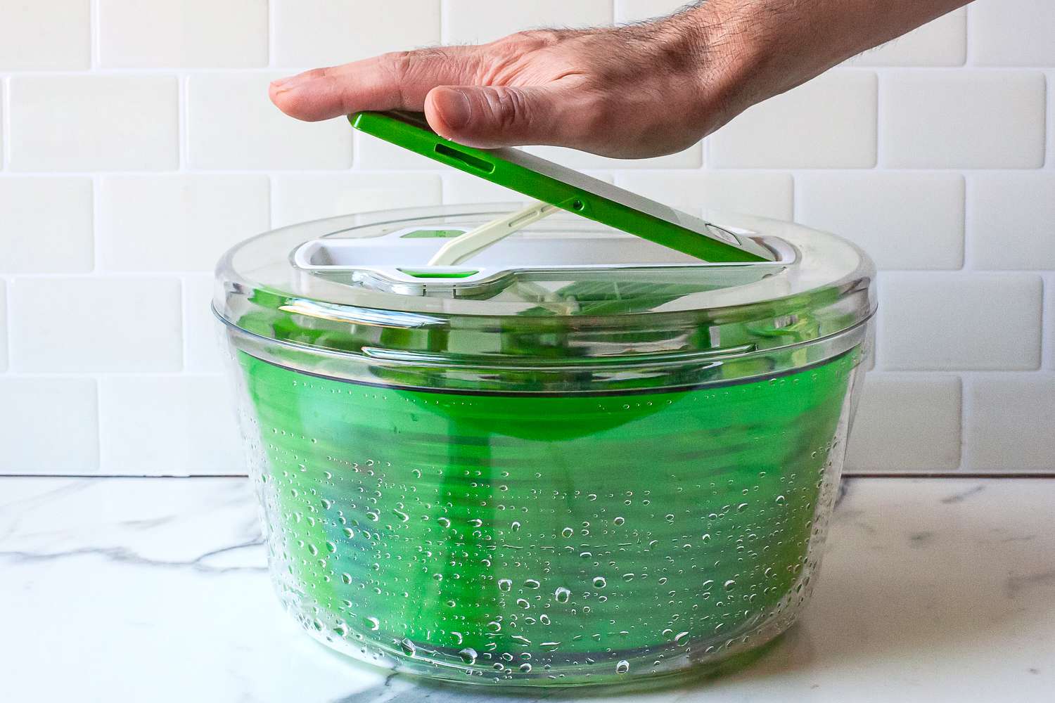 a person pumping the zyliss salad spinner