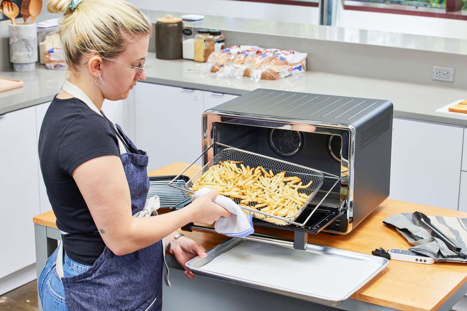 A person tossing fries cooking in the KitchenAid Dual Convection Countertop Oven with Air Fryer