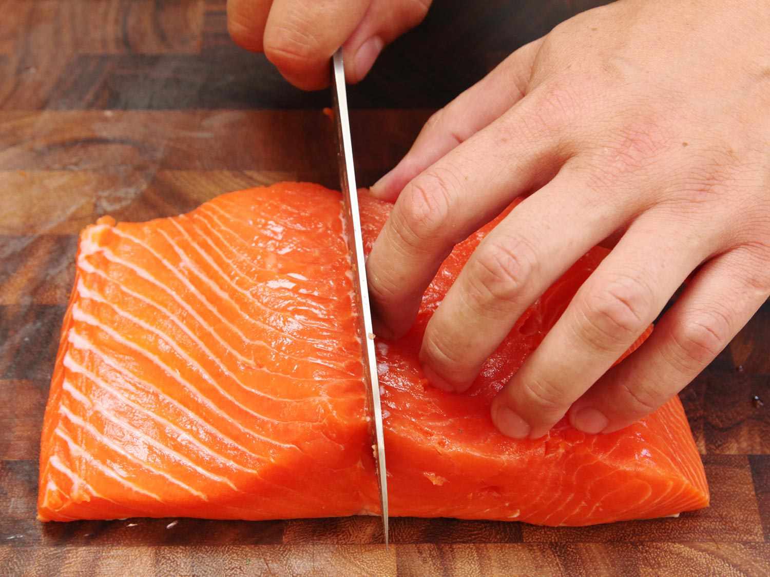 Photo showing slicing a large salmon fillet in half down the center.