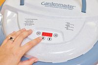 A person pressing a button of Nesco Gardenmaster Digital Pro Food Dehydrator