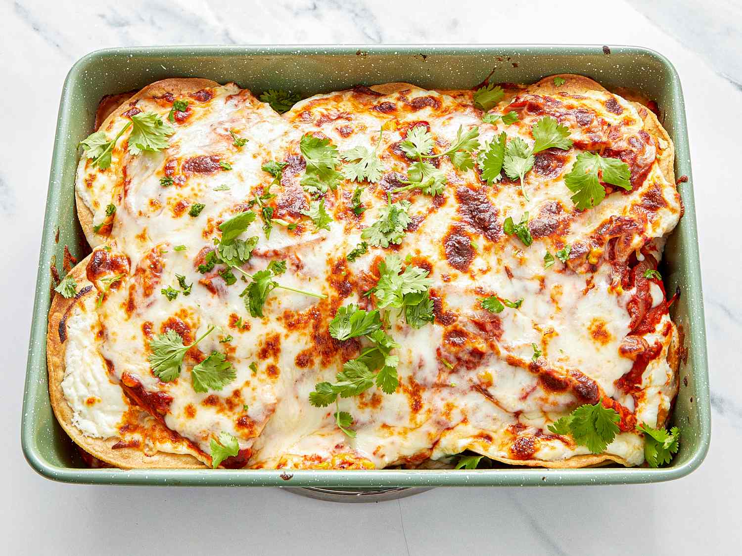A baked dish with melted cheese and garnished with fresh cilantro in a rectangular pan