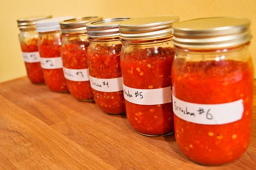 Six jars of sriracha testing varying amount of garlic, salt, and sugar.