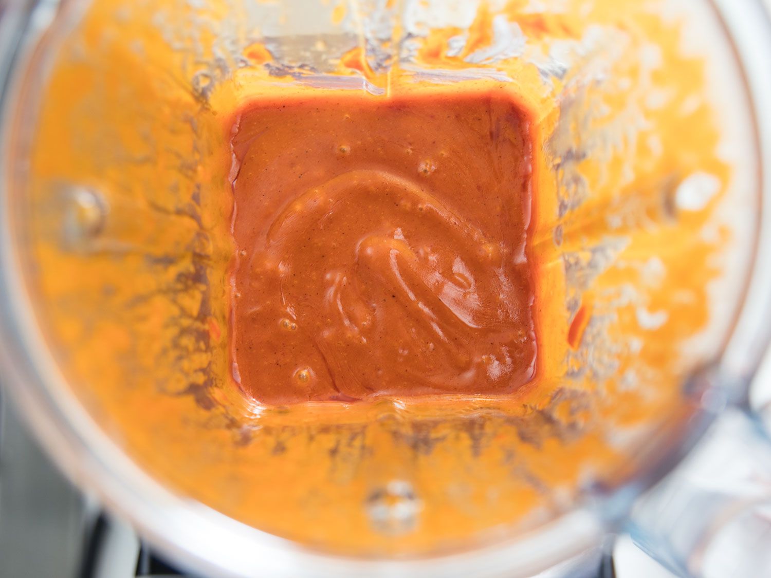 Orange-hued sauce of gochujang, garlic, gochugaru, and honey in the bowl of a blender.