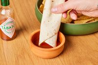 Person dipping tortilla into Tabasco Original Red Sauce