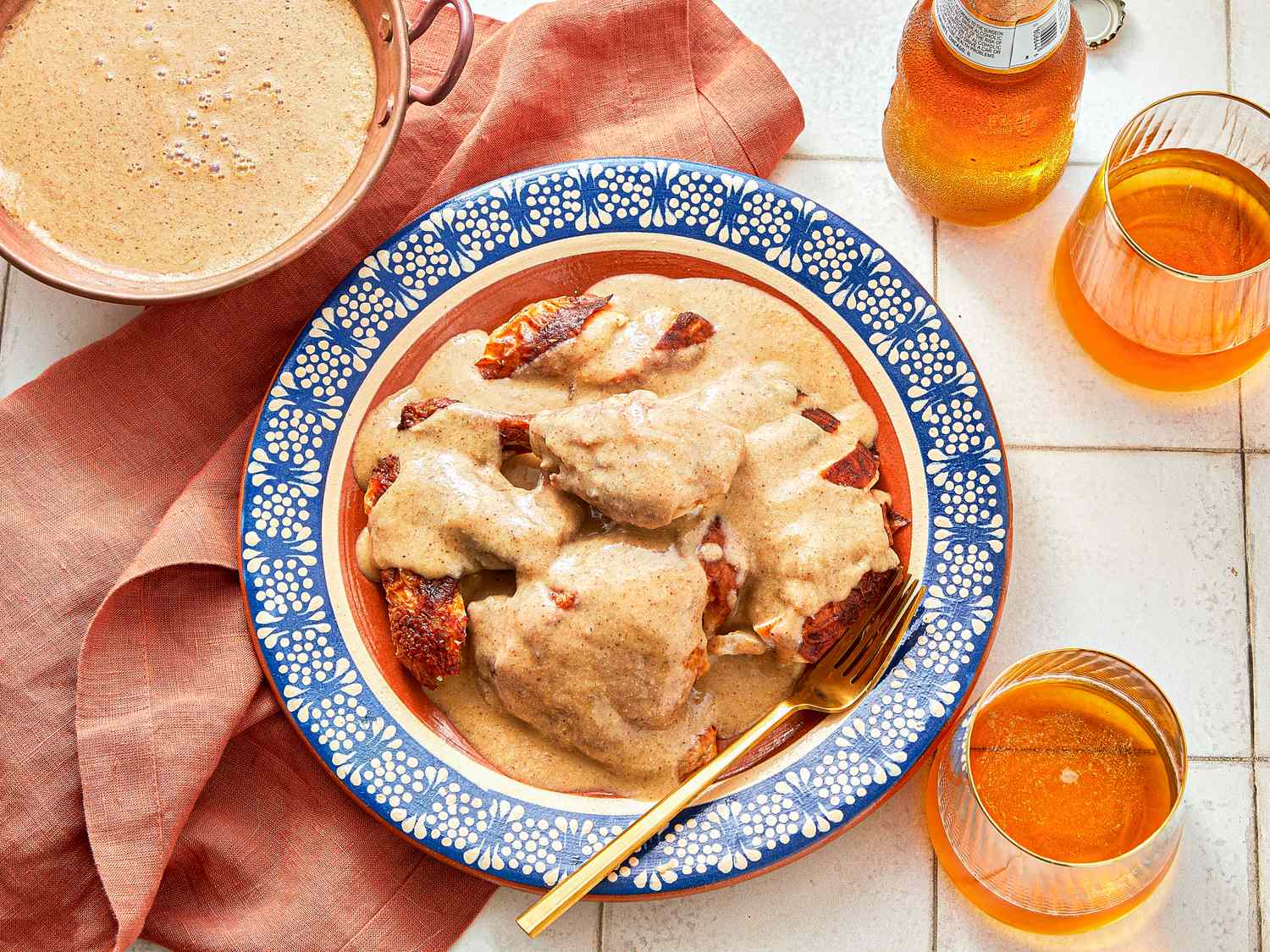 Mole blanco served on a decorated plate alongside a pink napkin and drinks