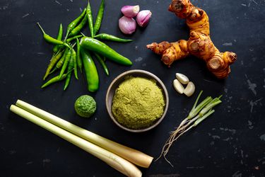 green curry paste in a small bowl with prominent ingredients surrounding it