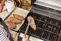 A person cooks meat on the Weber Spirit EX-325s Smart Grill