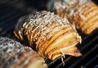 Closeup of Grilled Hasselback Potatoes With Garlic and Parmesan cooking on a grill grate.