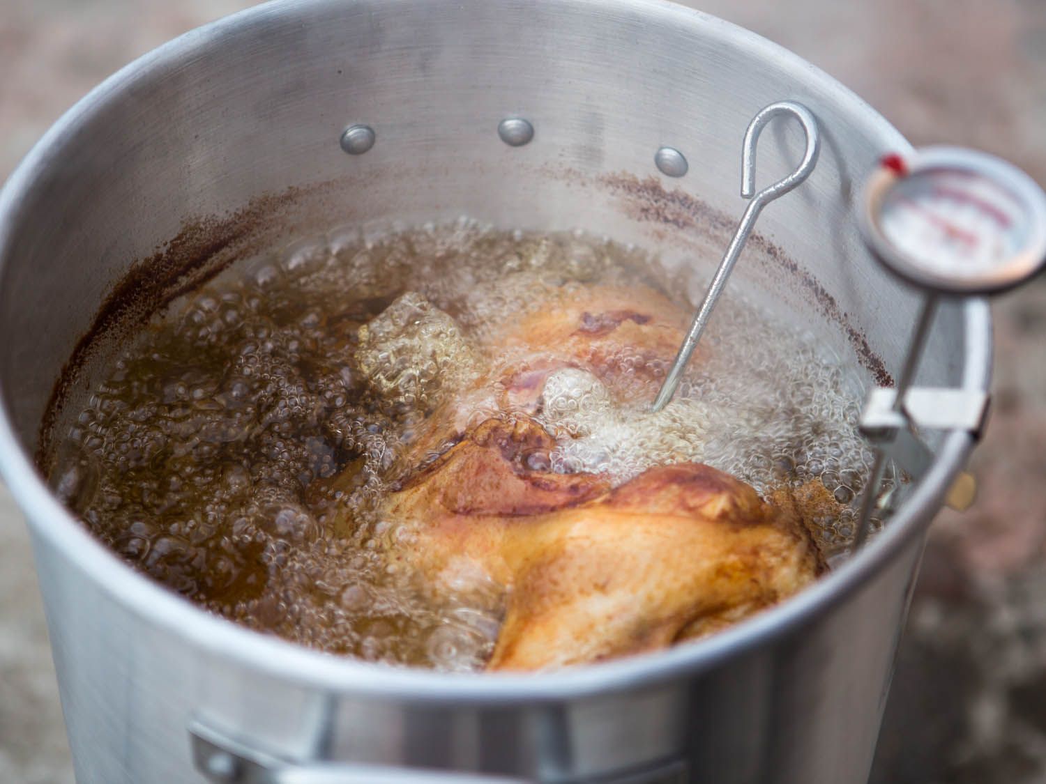 A turkey deep frying in a large pot of boiling oil.