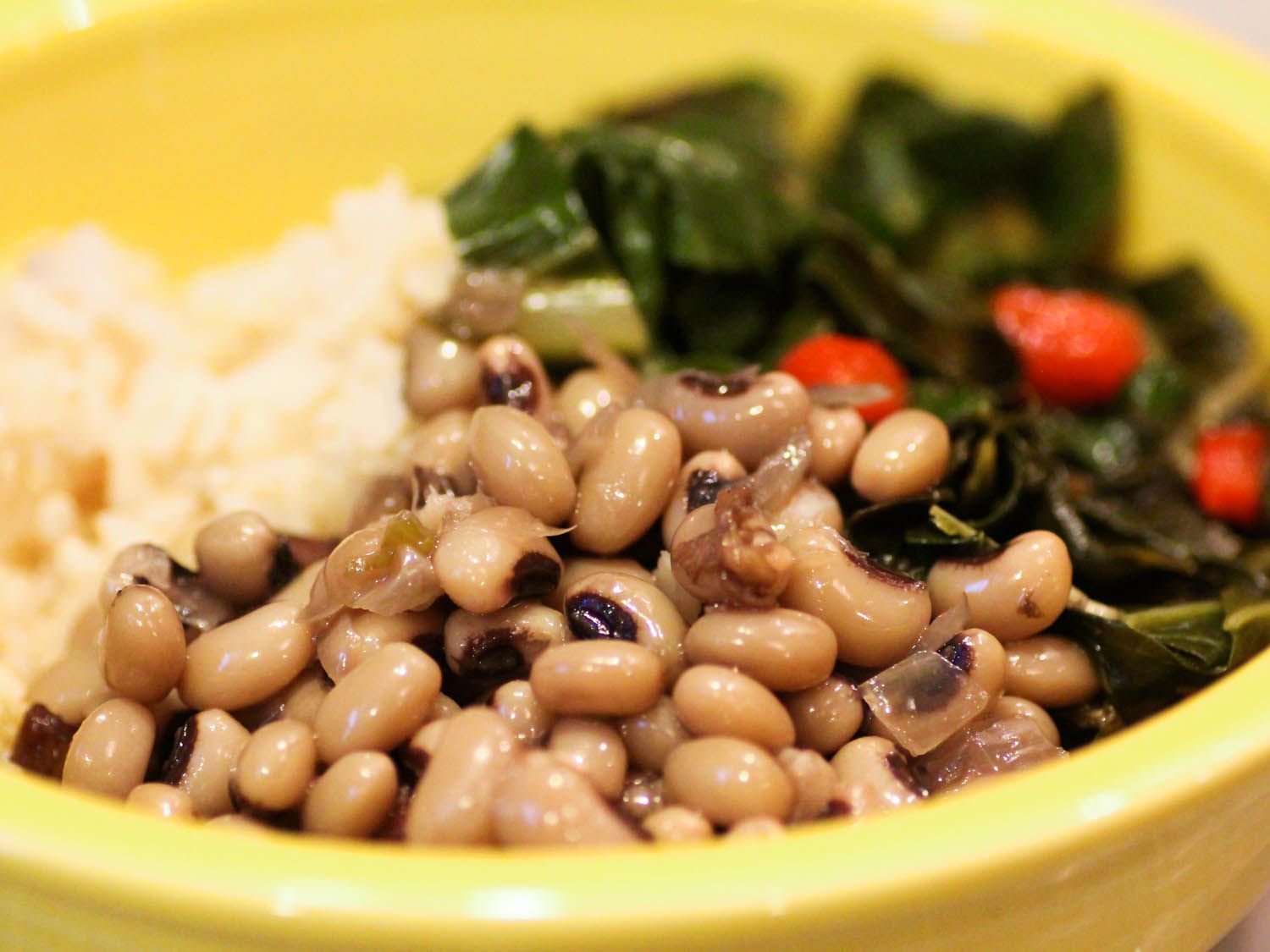 Closeup of stewed black-eyed peas, served alongside braised collard greens.