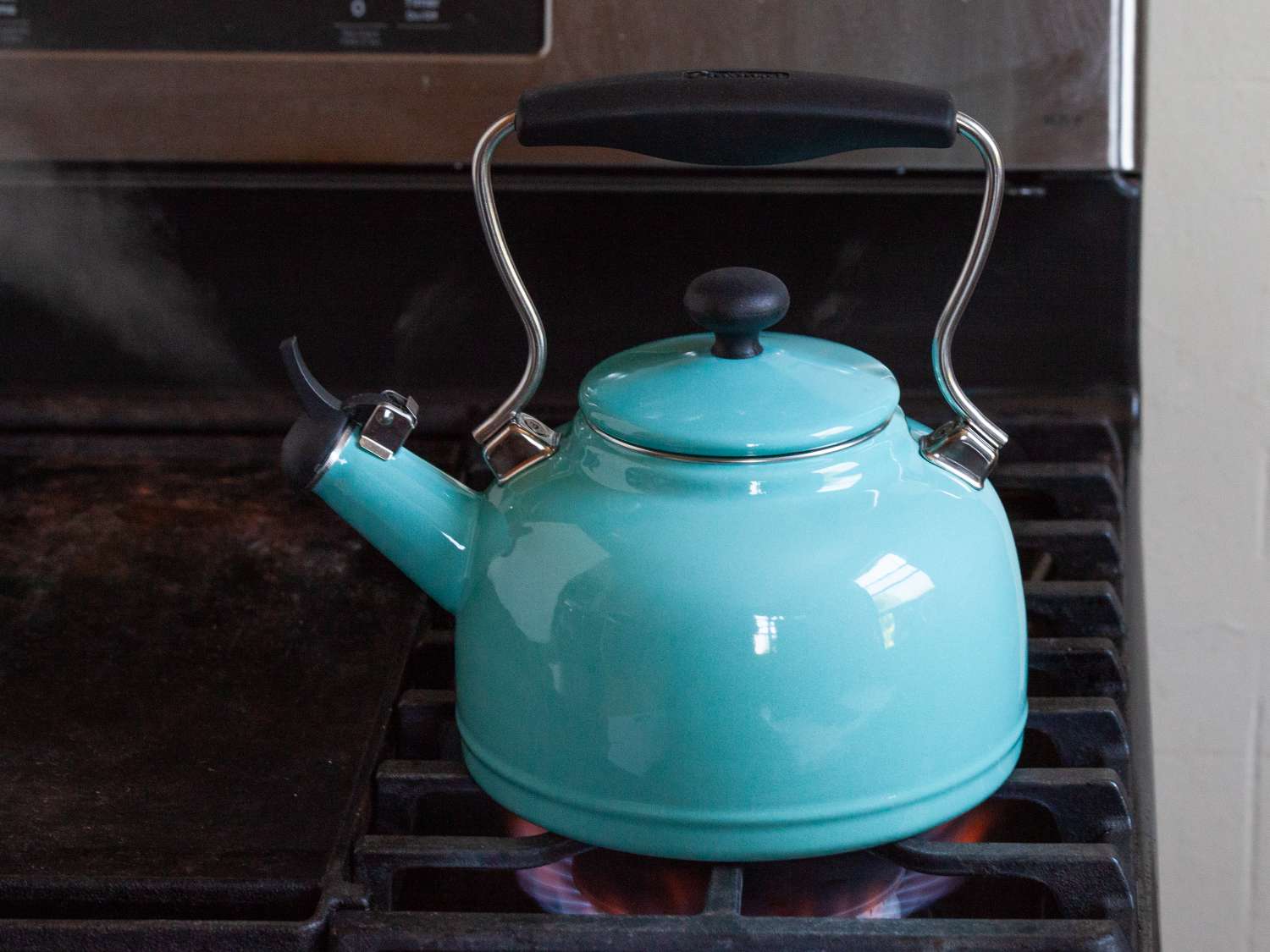 a blue kettle with steam coming out of the spout on a stove