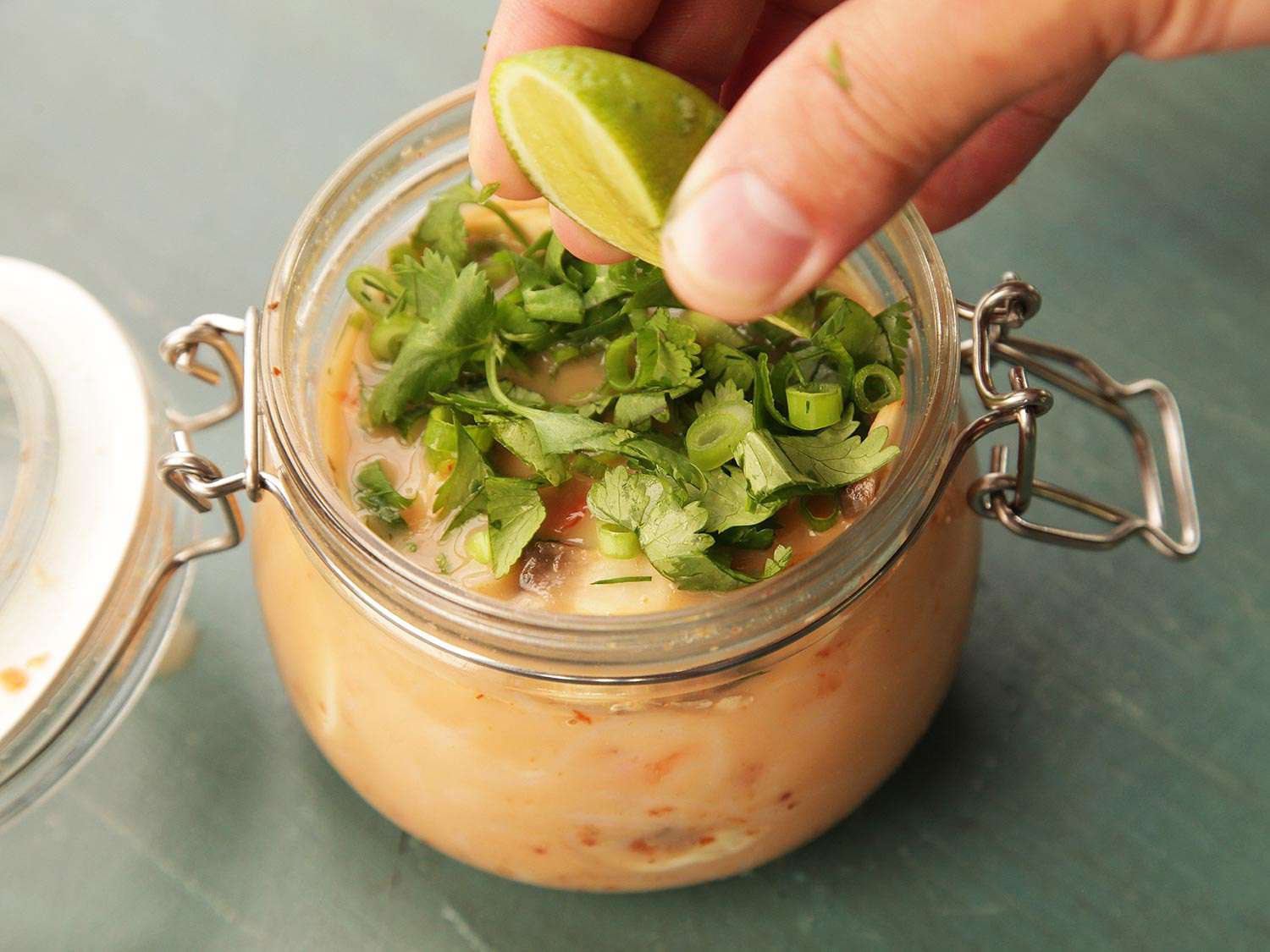 The finished jar of Thai curry coconut shrimp flavor instant noodles, garnished with herbs and a squeeze of lime.
