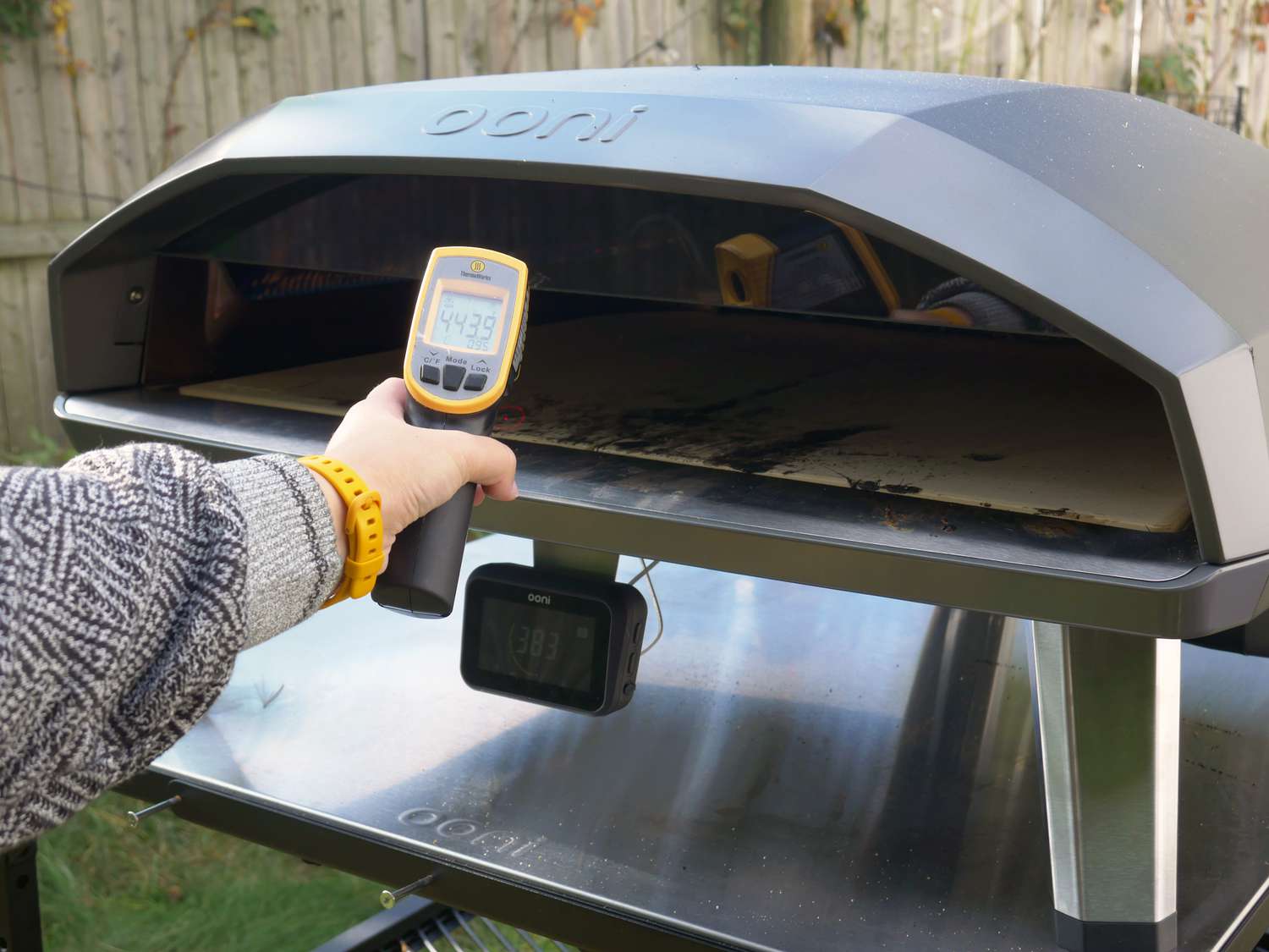 a person using an infrared thermometer to take the temperature of the pizza oven