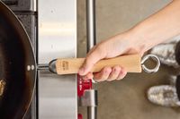 A person holds the Joyce Chen Carbon Steel Wok by the wooden handle