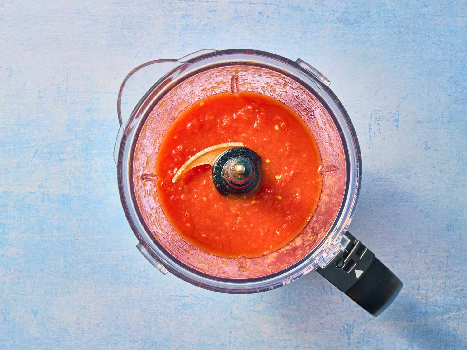 tomato sauce in food processor on blue tabletop 