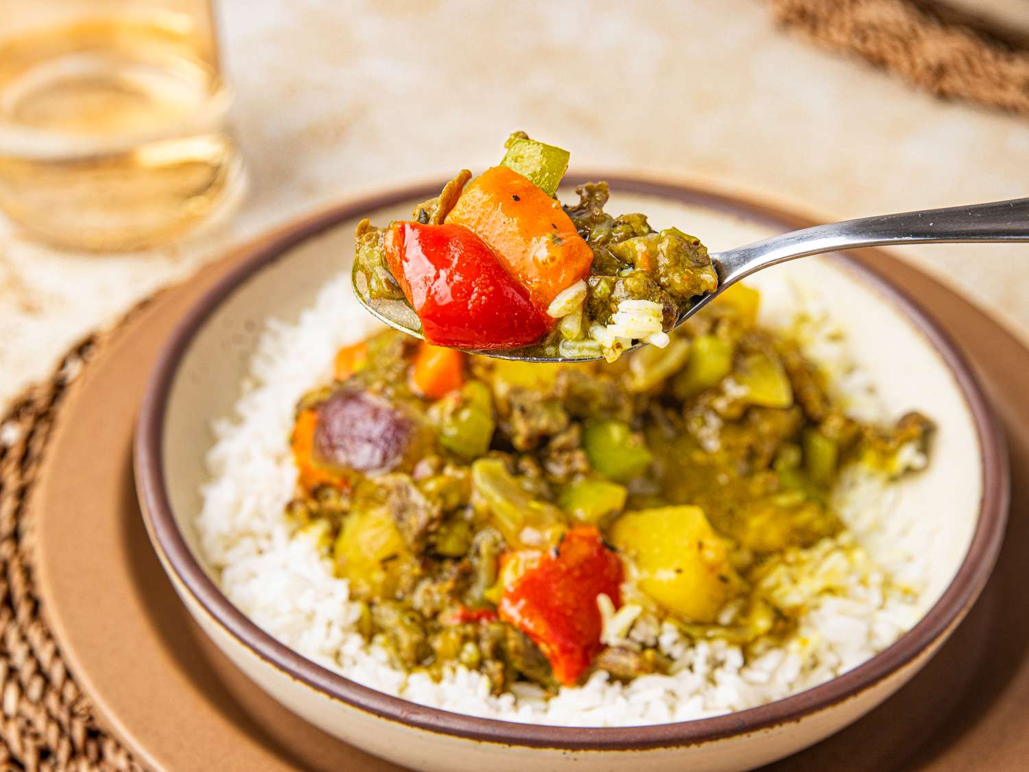 Nigerian beef curry served over rice in a bowl a spoon lifting a portion