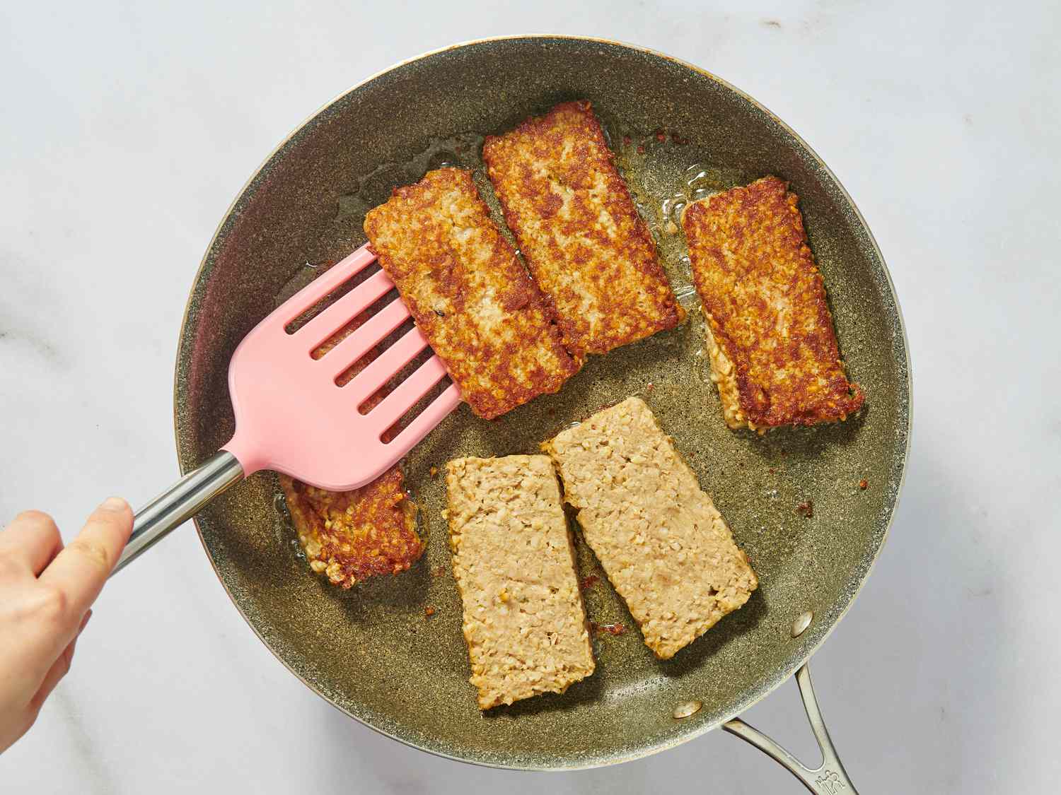 flipping goetta with spatula while it fries in a pan