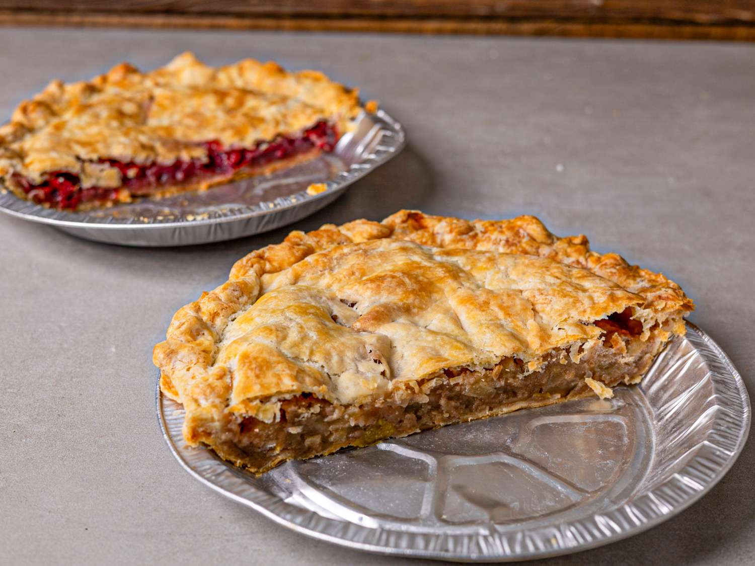 Two pies on a table one with a slice missing showing the filling of each pie