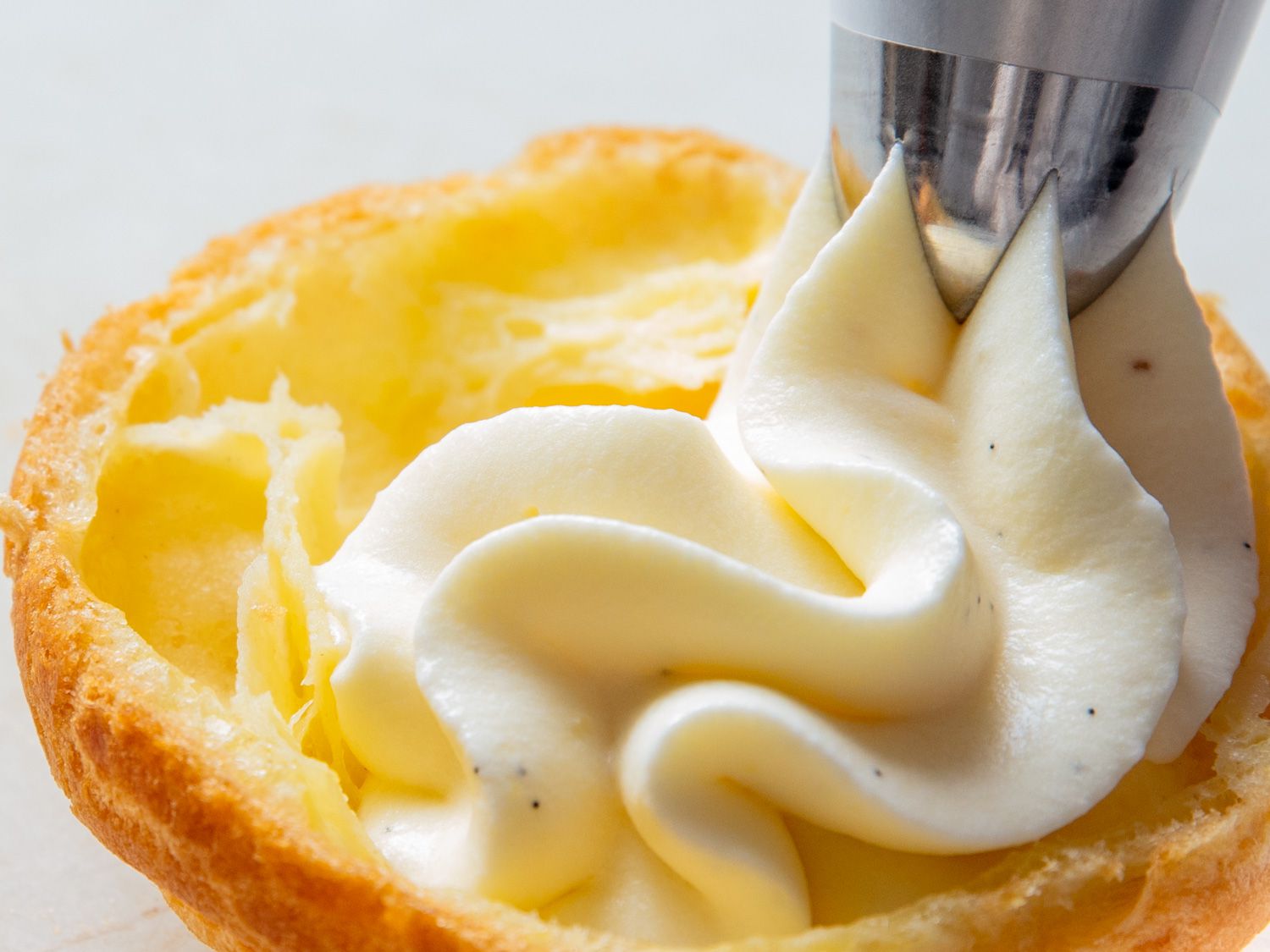 Piping creme legere on a cream puff shell half.