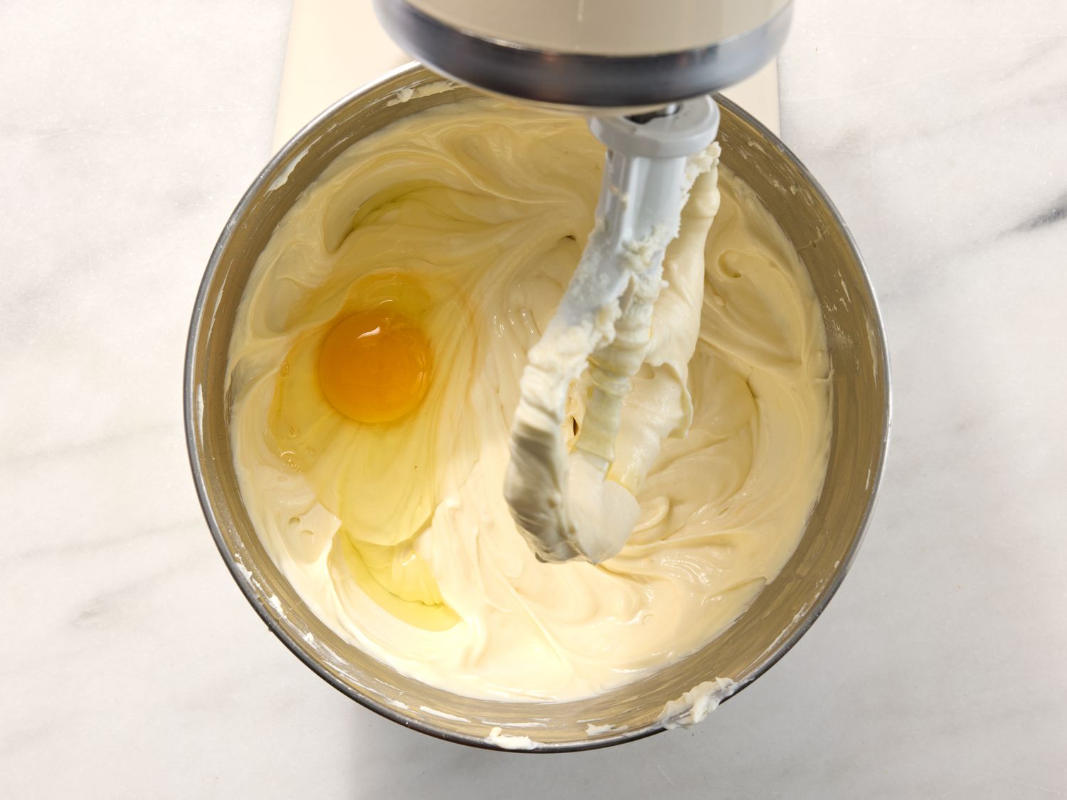 Eggs added into mixture stirring on stand mixer 