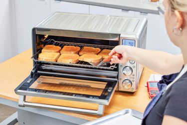 A person removing toast from the Breville the Smart Oven Air Fryer