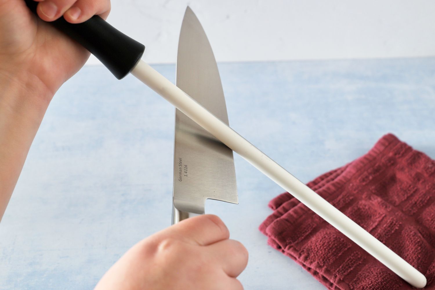 Hands holding a kitchen knife and a honing steel during the sharpening process
