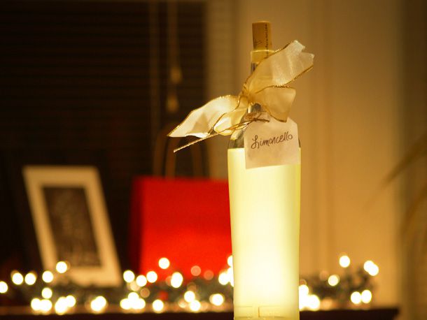 A labeled bottle of limoncello, deecorated with a bow and backlit by Christmas lights.