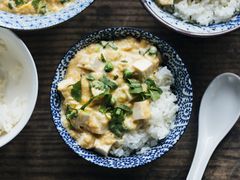 Overhead view of slippery eggs with tofu and peas in a blue patterned bowl
